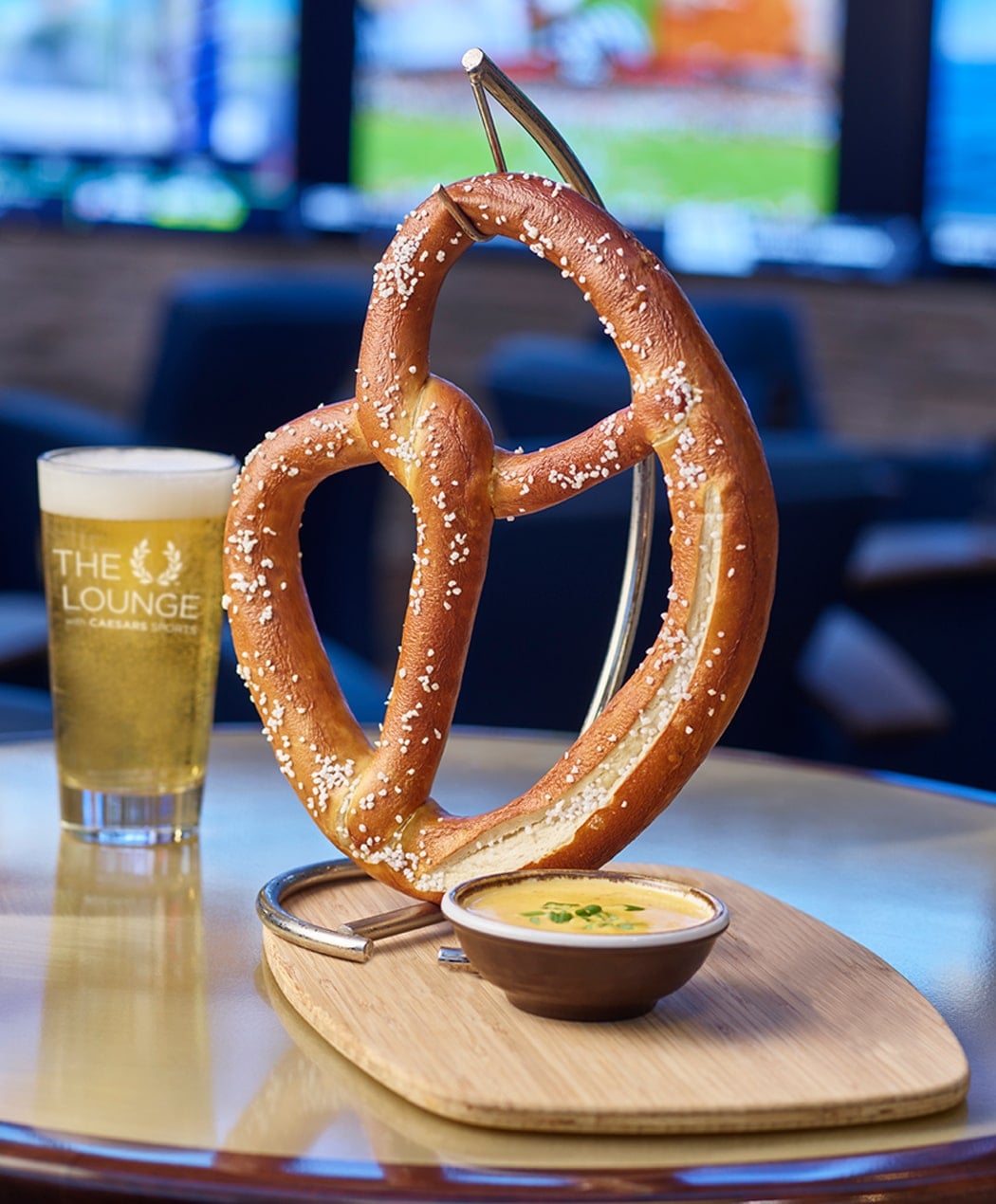 large pretzel with cheese and a pint glass of beer at the lounge with caesars sports